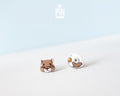 Mismatched hand-painted wooden stud earrings featuring a brown hamster face and a white exercise wheel