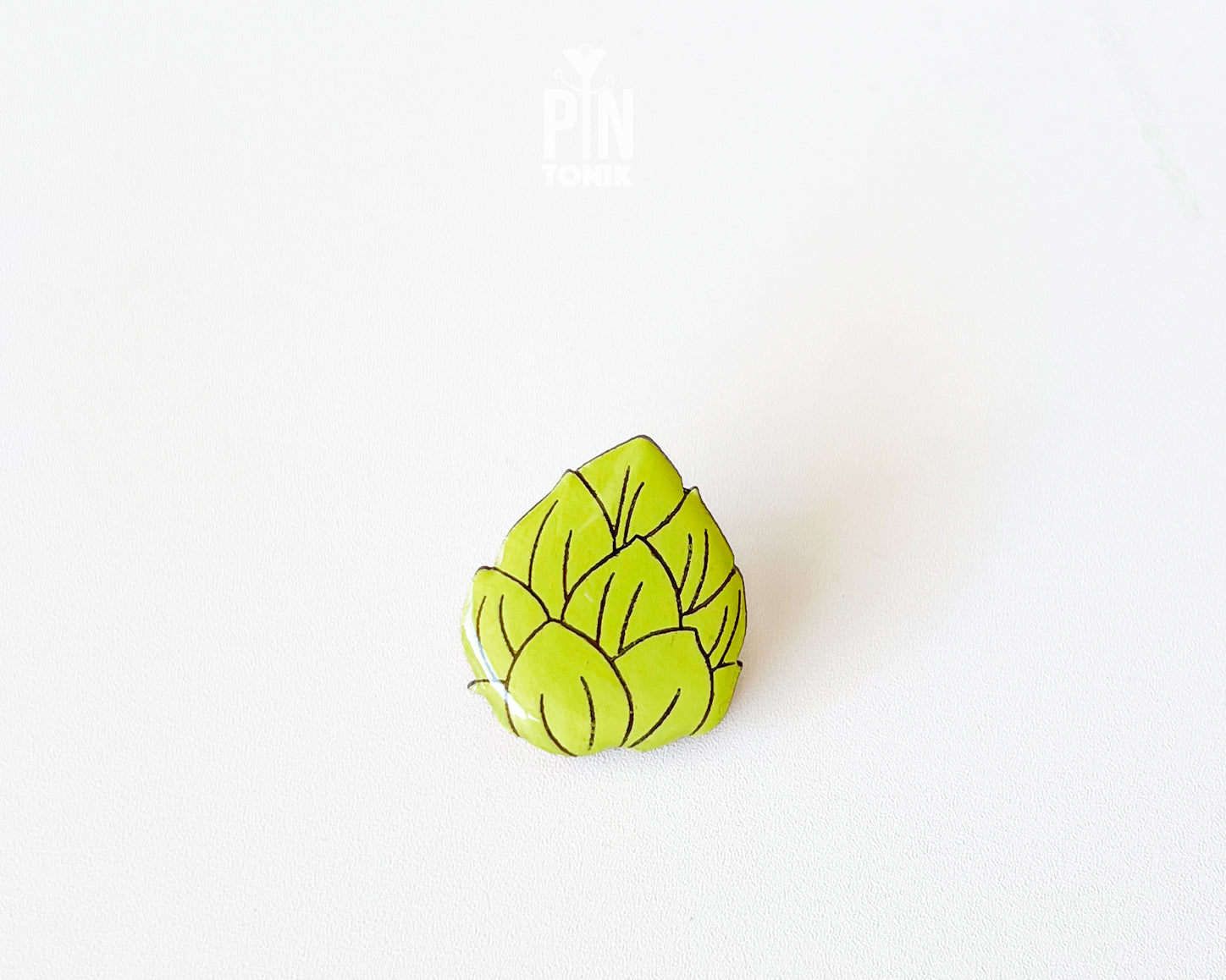 Hand-painted wooden beer hops pin with bright green layered leaves and a glossy finish, shown next to a stainless steel clutch back on a white background.