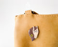 Hand-painted wooden horse pin with a flower in its mane and a funny side-eye expression, finished with glossy resin