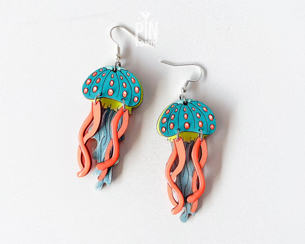 Hand-painted wooden jellyfish dangle earrings with teal caps, coral tentacles, and sterling silver hooks, finished in glossy resin