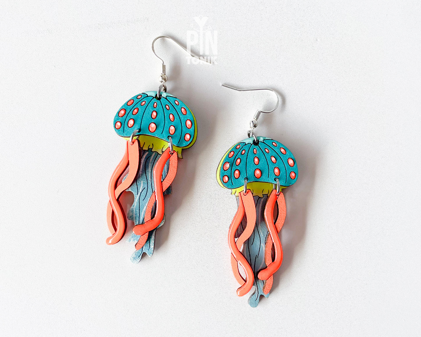 Hand-painted wooden jellyfish dangle earrings with teal caps, coral tentacles, and sterling silver hooks, finished in glossy resin
