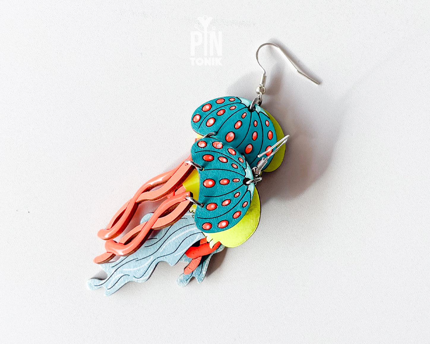 Hand-painted wooden jellyfish dangle earrings with teal caps, coral tentacles, and sterling silver hooks, finished in glossy resin