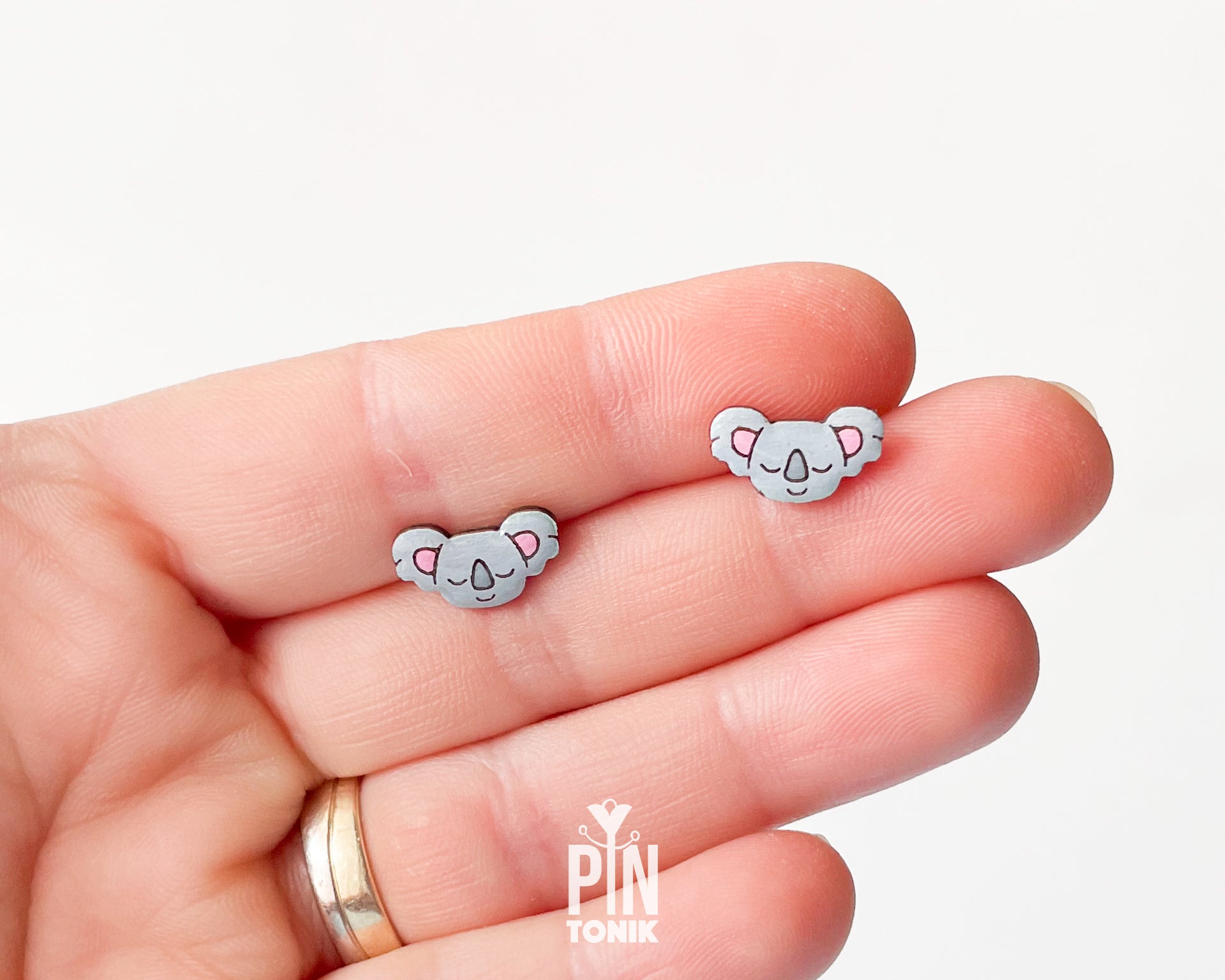 Pair of hand-painted wooden koala stud earrings with pink ears and peaceful closed eyes, finished with glossy resin