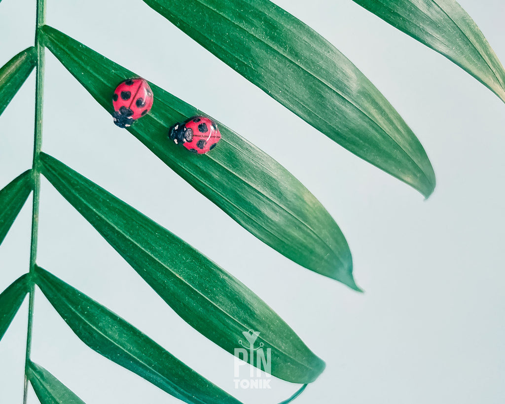 Handmade tiny wooden ladybug stud earrings in classic red and black, measuring a realistic 7-8mm by PinTonik.