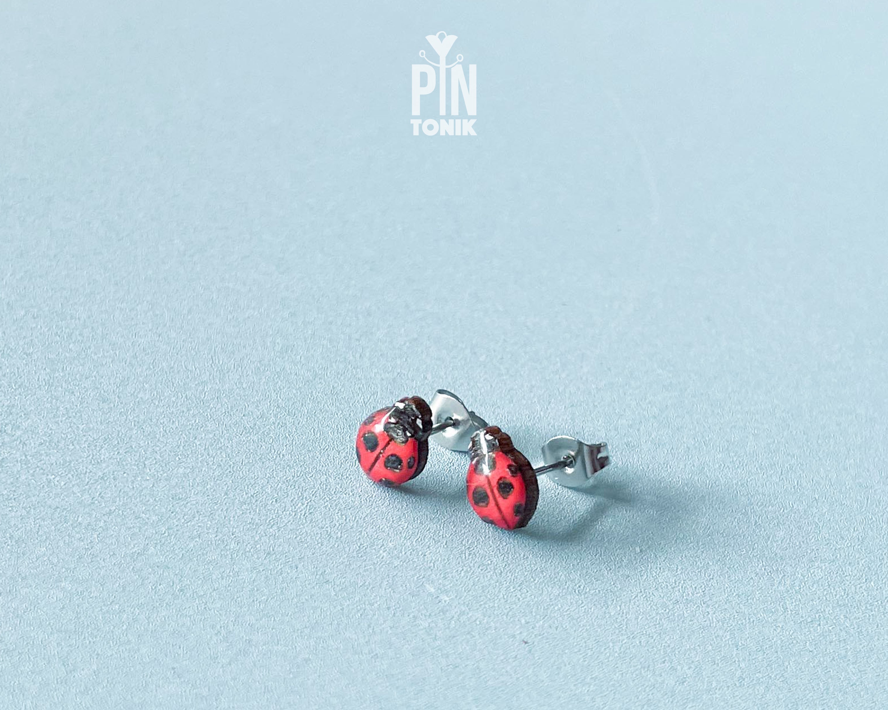 Handmade tiny wooden ladybug stud earrings in classic red and black, measuring a realistic 7-8mm by PinTonik.