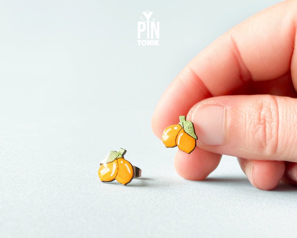 Hand-painted lemon wooden stud earrings on a light blue background, showcasing vibrant yellow citrus design and high-gloss finish.