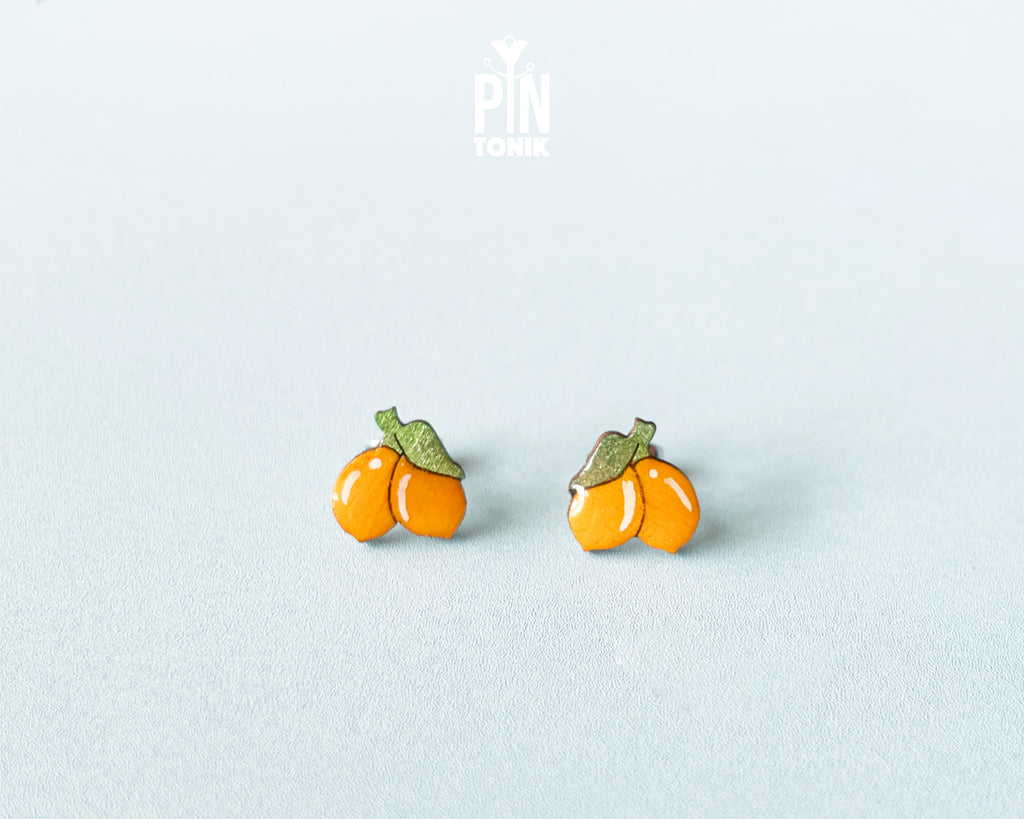 Hand-painted lemon wooden stud earrings on a light blue background, showcasing vibrant yellow citrus design and high-gloss finish.