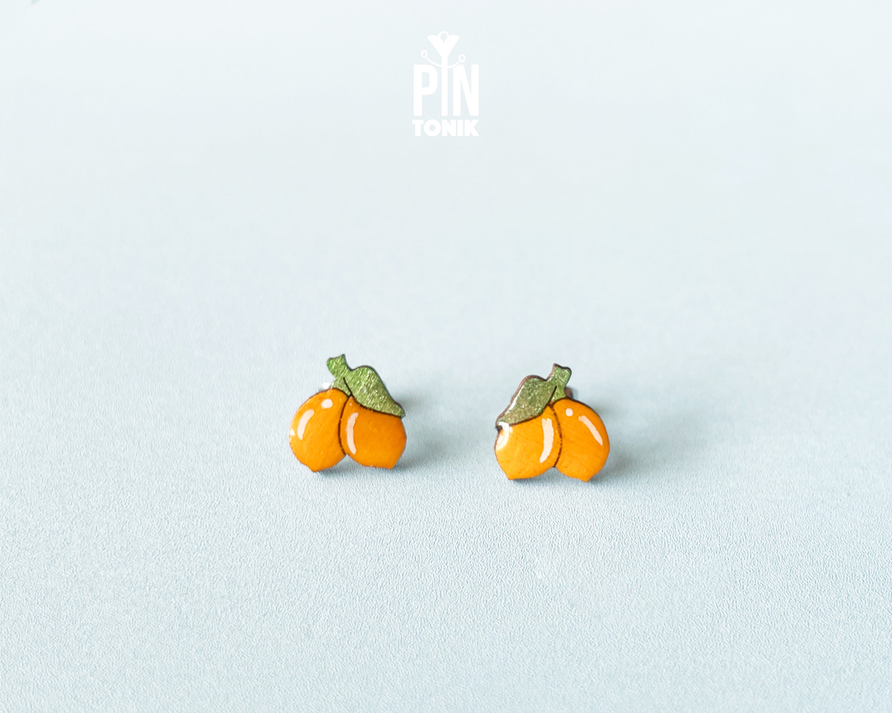 Hand-painted lemon wooden stud earrings on a light blue background, showcasing vibrant yellow citrus design and high-gloss finish.