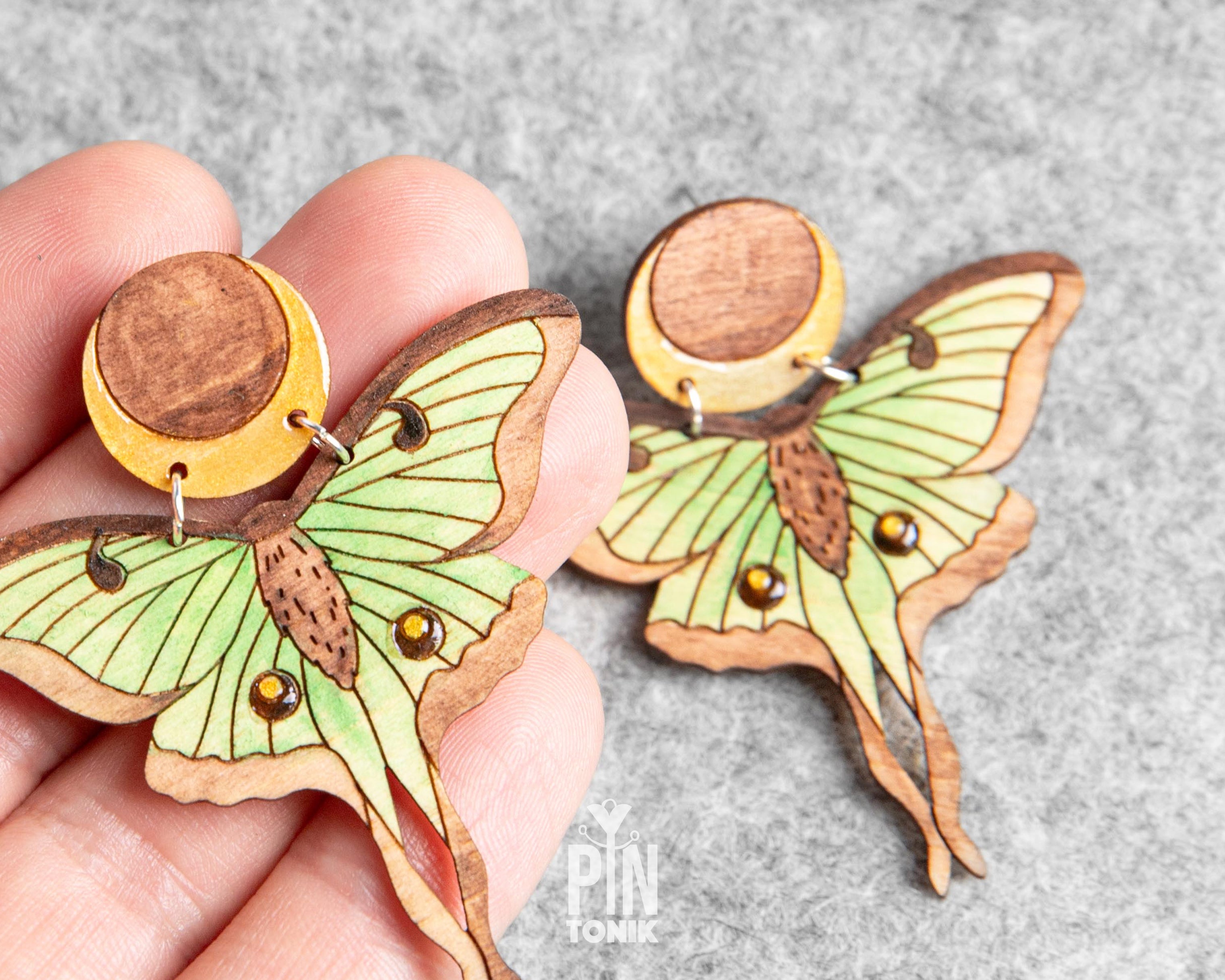 Hand-painted wooden Luna Moth stud earrings featuring green wings and a natural wood-grain moon detail with stainless steel posts