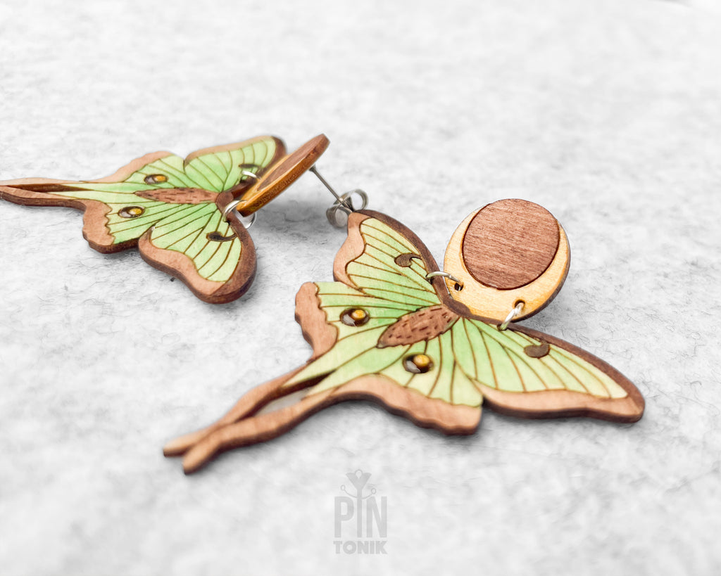 Hand-painted wooden Luna Moth stud earrings featuring green wings and a natural wood-grain moon detail with stainless steel posts