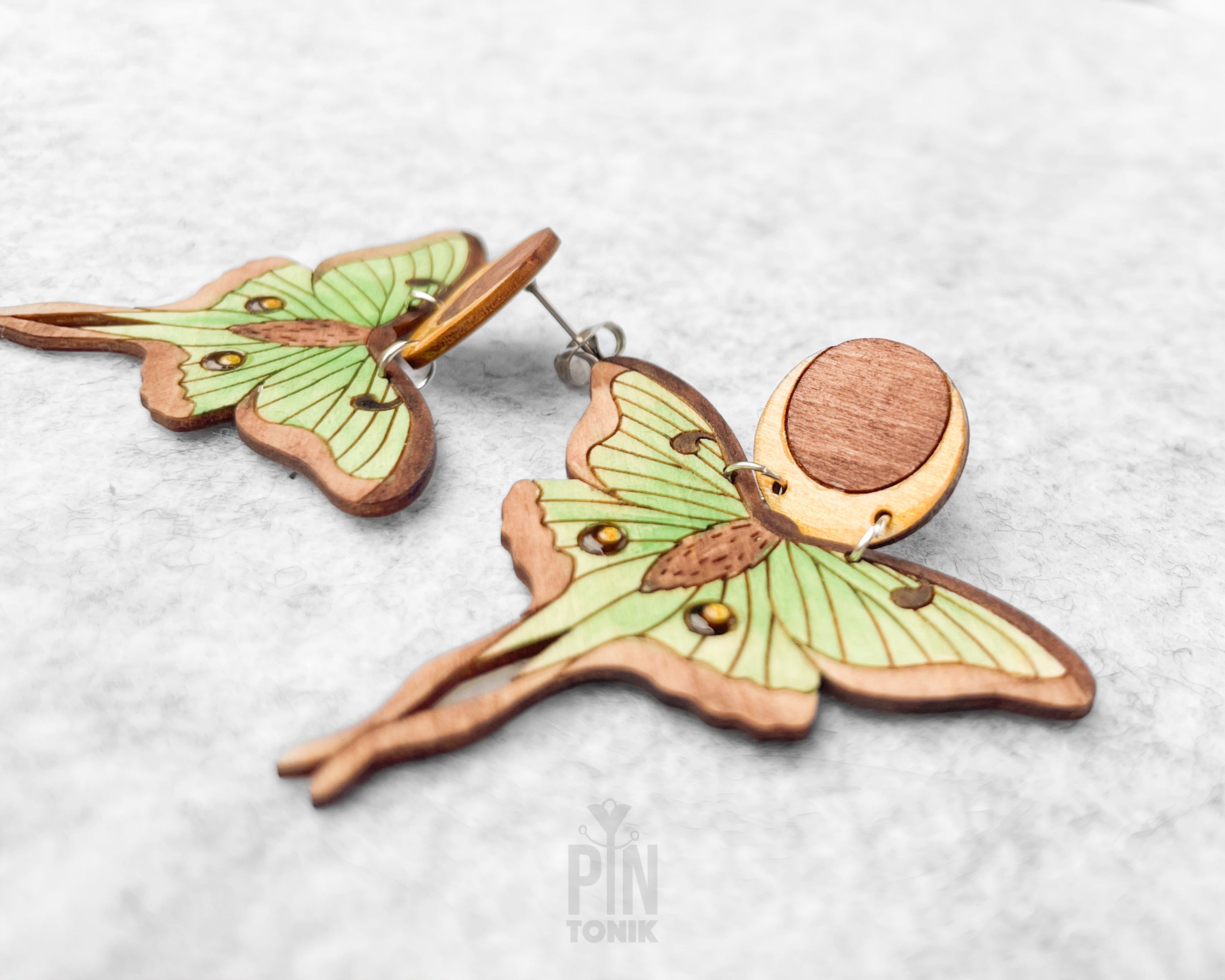 Hand-painted wooden Luna Moth stud earrings featuring green wings and a natural wood-grain moon detail with stainless steel posts