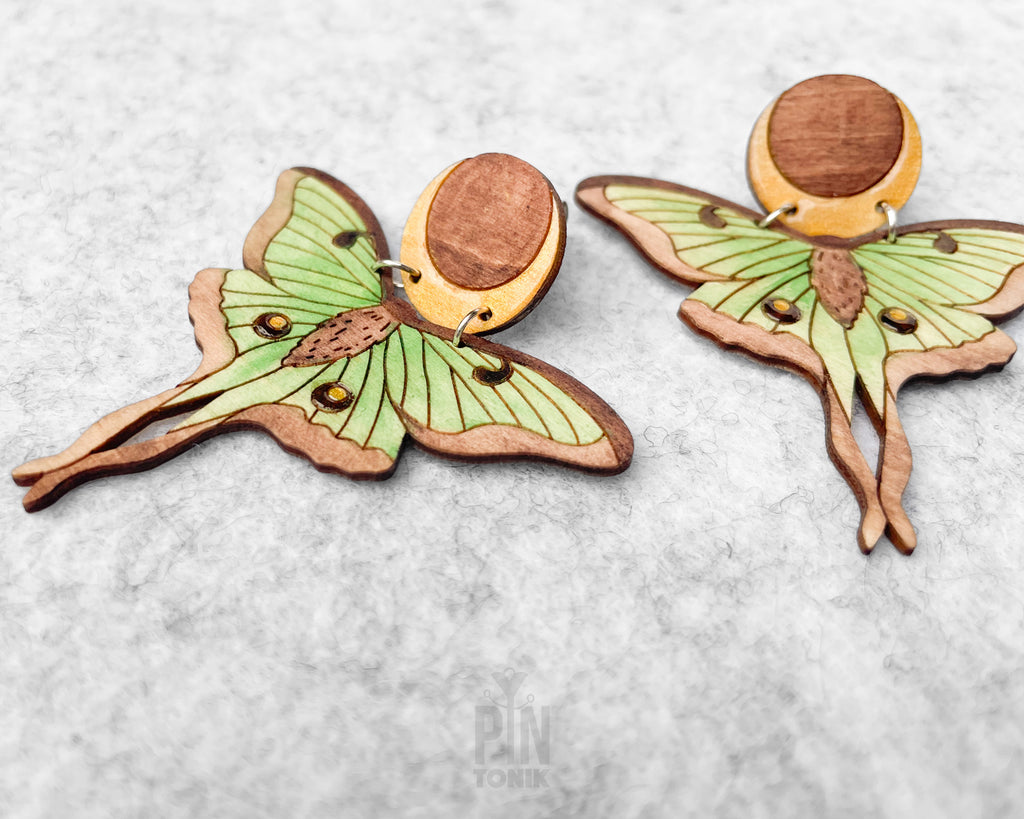 Hand-painted wooden Luna Moth stud earrings featuring green wings and a natural wood-grain moon detail with stainless steel posts
