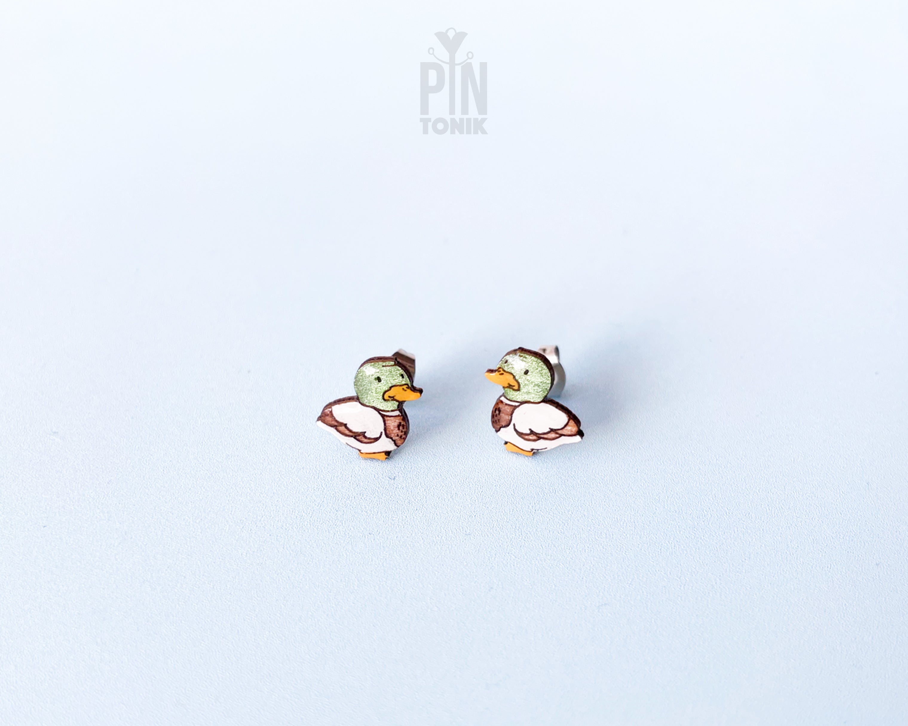 Pair of hand-painted wooden mallard duck stud earrings featuring a green head and brown body with a glossy resin finish