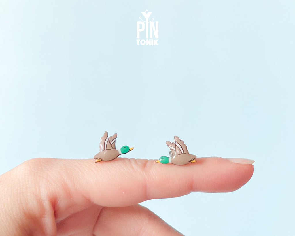Pair of hand-painted wooden flying mallard duck stud earrings with wings spread and a glossy resin finish