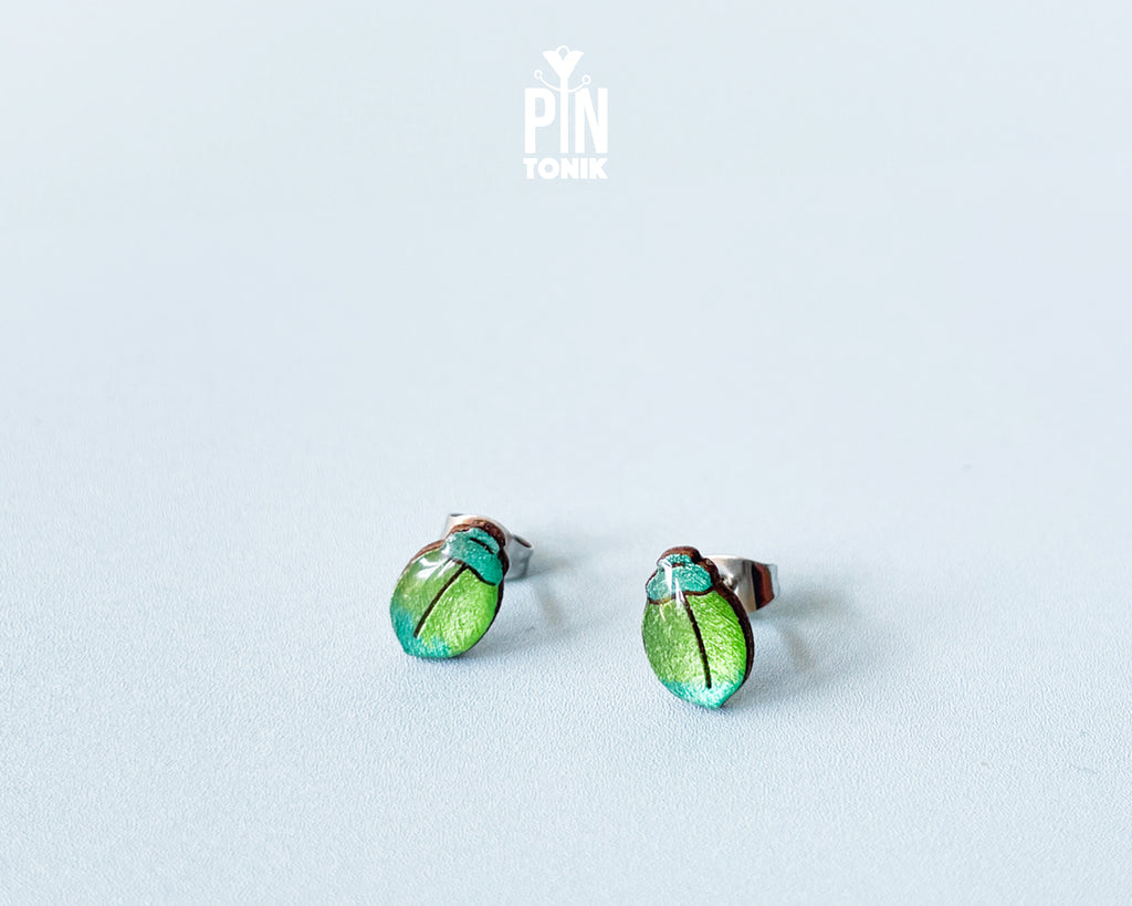 Handmade wooden milkweed beetle stud earrings with a shimmering iridescent green and blue finish by PinTonik.