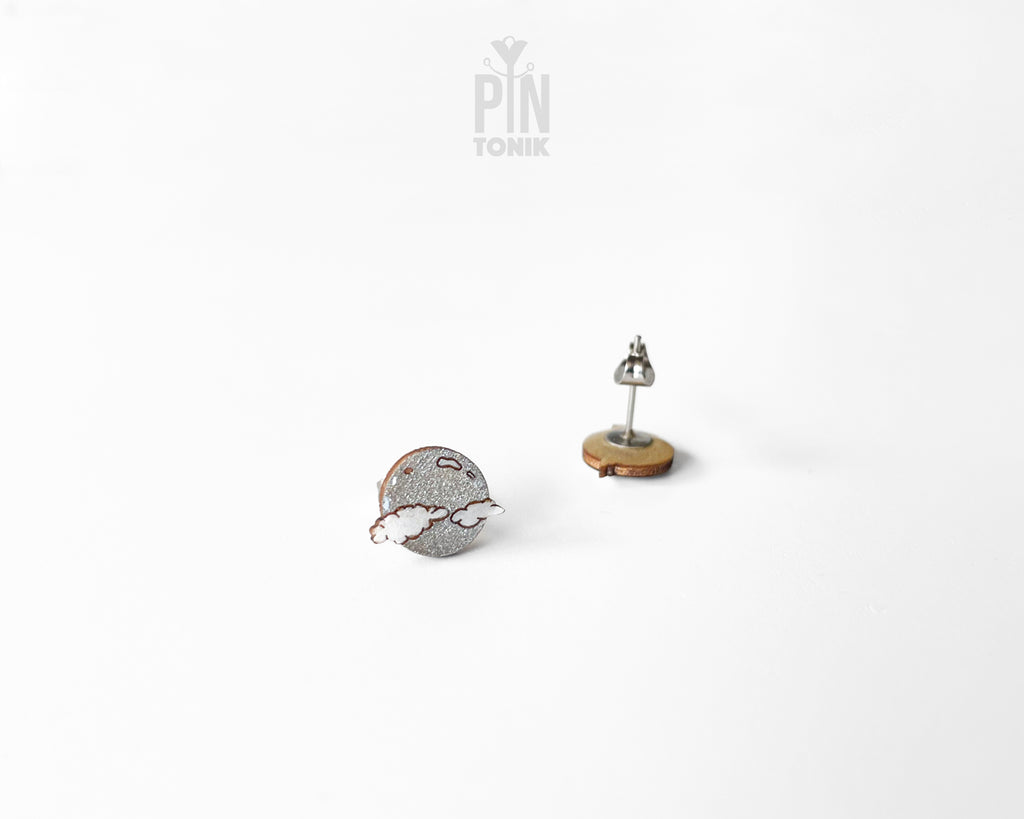 Handmade wooden celestial stud earrings featuring a silver glitter crescent moon behind a white cloud by PinTonik.