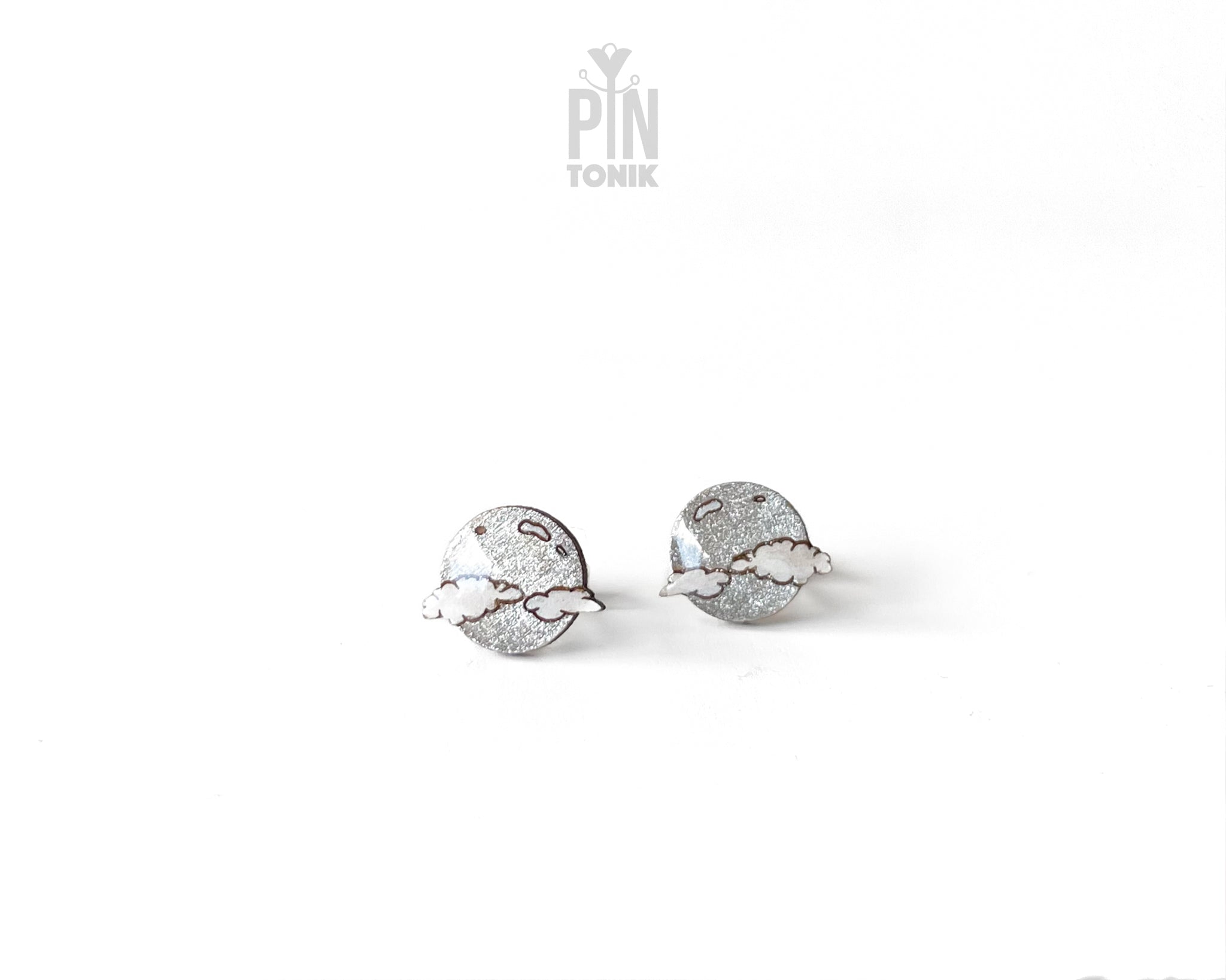 Handmade wooden celestial stud earrings featuring a silver glitter crescent moon behind a white cloud by PinTonik.