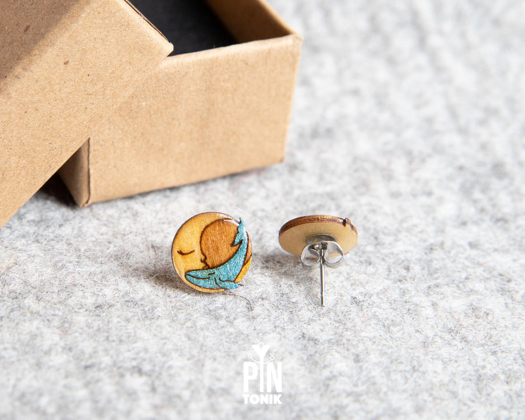 Handmade wooden stud earrings featuring a little blue whale sleeping inside a yellow crescent moon by PinTonik.
