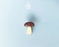 Hand-painted wooden porcini mushroom pin with a dark brown cap and cream-colored stem, shown on a light blue background