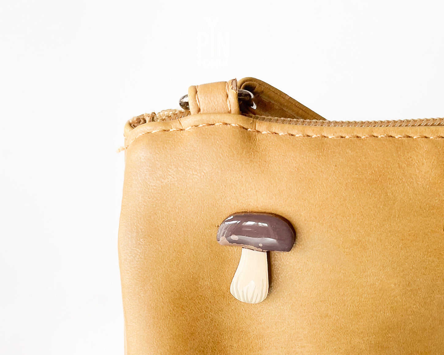 Hand-painted wooden porcini mushroom pin with a dark brown cap and cream-colored stem, shown on a light blue background