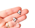 Pair of hand-painted wooden climbing panda stud earrings that appear to be hanging from the earlobe, finished with glossy resin