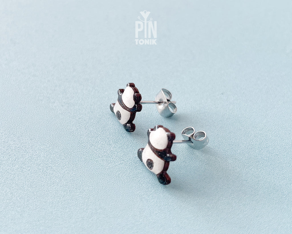 Pair of hand-painted wooden climbing panda stud earrings that appear to be hanging from the earlobe, finished with glossy resin