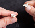 Handmade wooden paper airplane stud earrings in bright white with fine black hand-drawn crease lines by PinTonik.