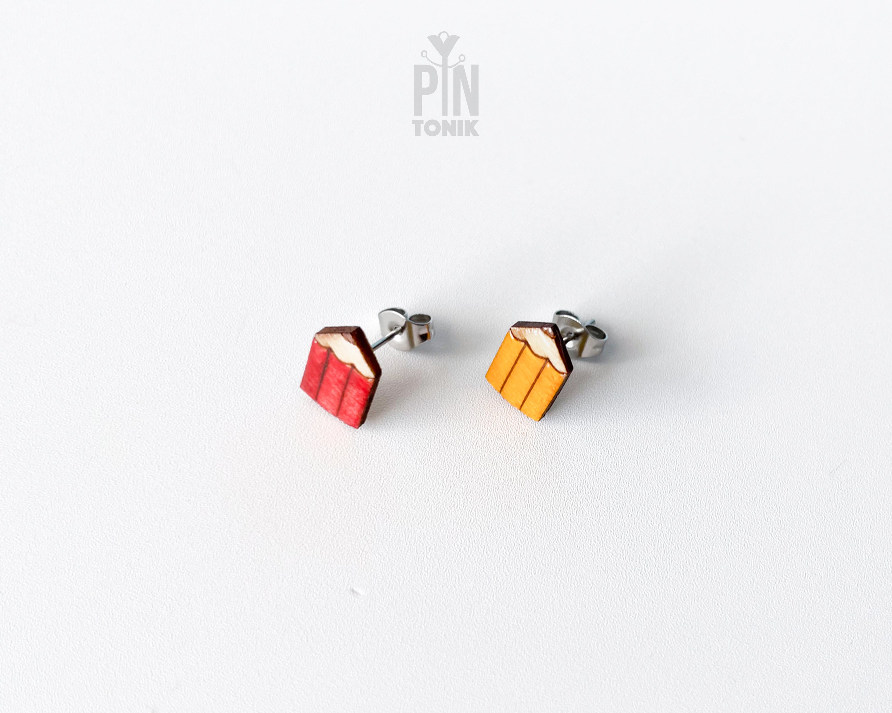 Handmade wooden mismatched stud earrings featuring a sharpened red colored pencil on one ear and yellow pencil on the other by PinTonik.