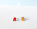 Handmade wooden mismatched stud earrings featuring a sharpened red colored pencil on one ear and yellow pencil on the other by PinTonik.