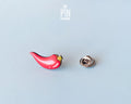 Hand-painted wooden red chili pepper pin with a glossy finish and a yellow stem, shown next to its stainless steel clutch back on a light blue-grey background