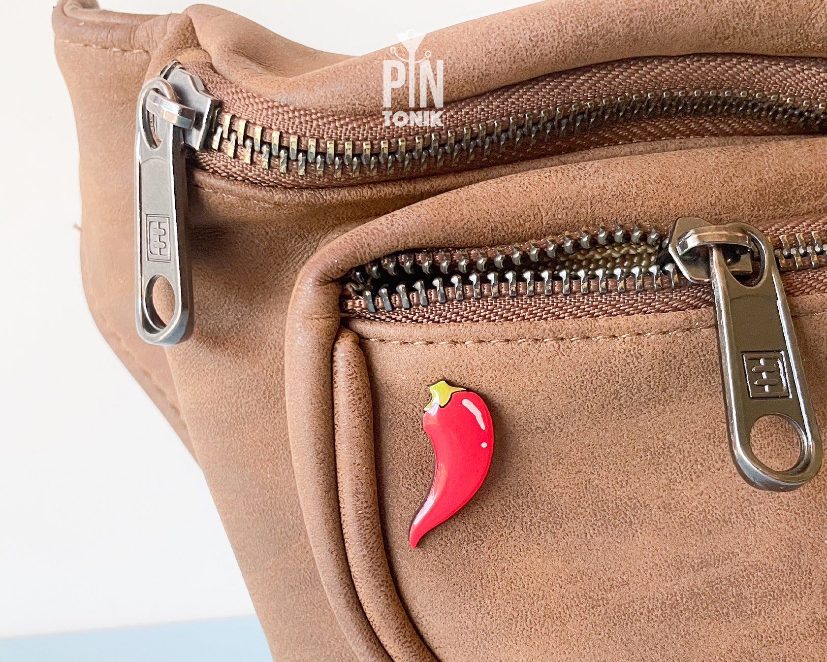 Hand-painted wooden red chili pepper pin with a glossy finish and a yellow stem, shown next to its stainless steel clutch back on a light blue-grey background