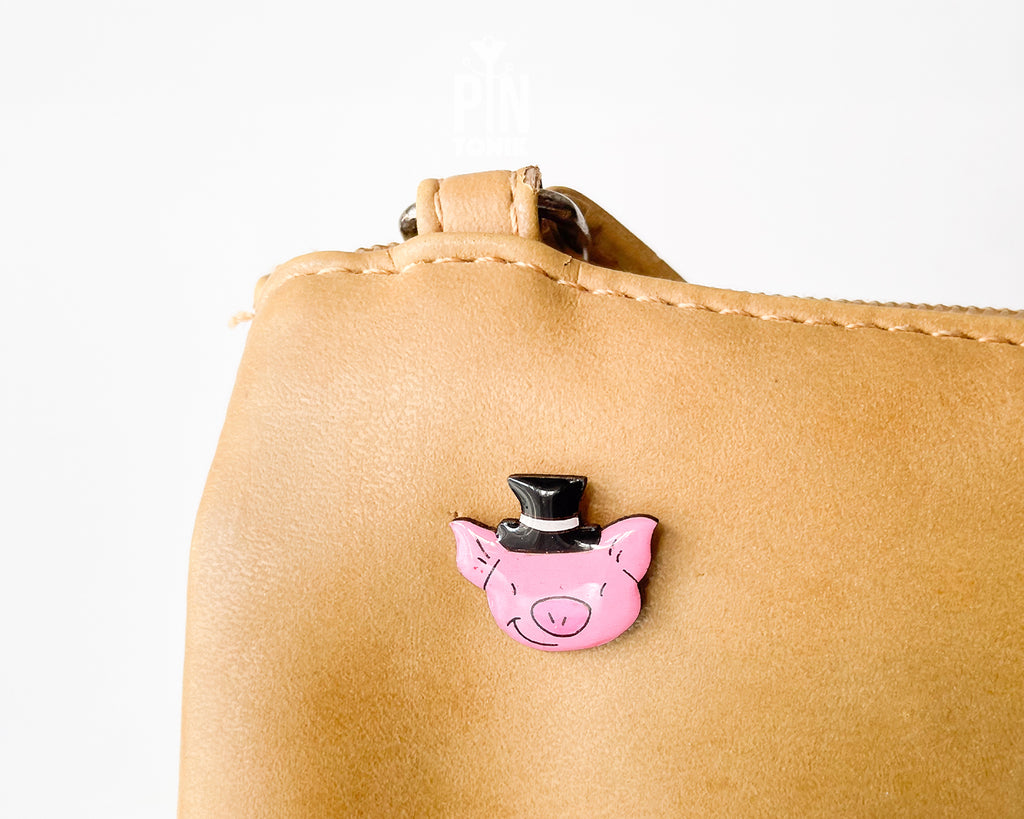 Hand-painted pink wooden pig pin wearing a black top hat with a high-gloss resin finish