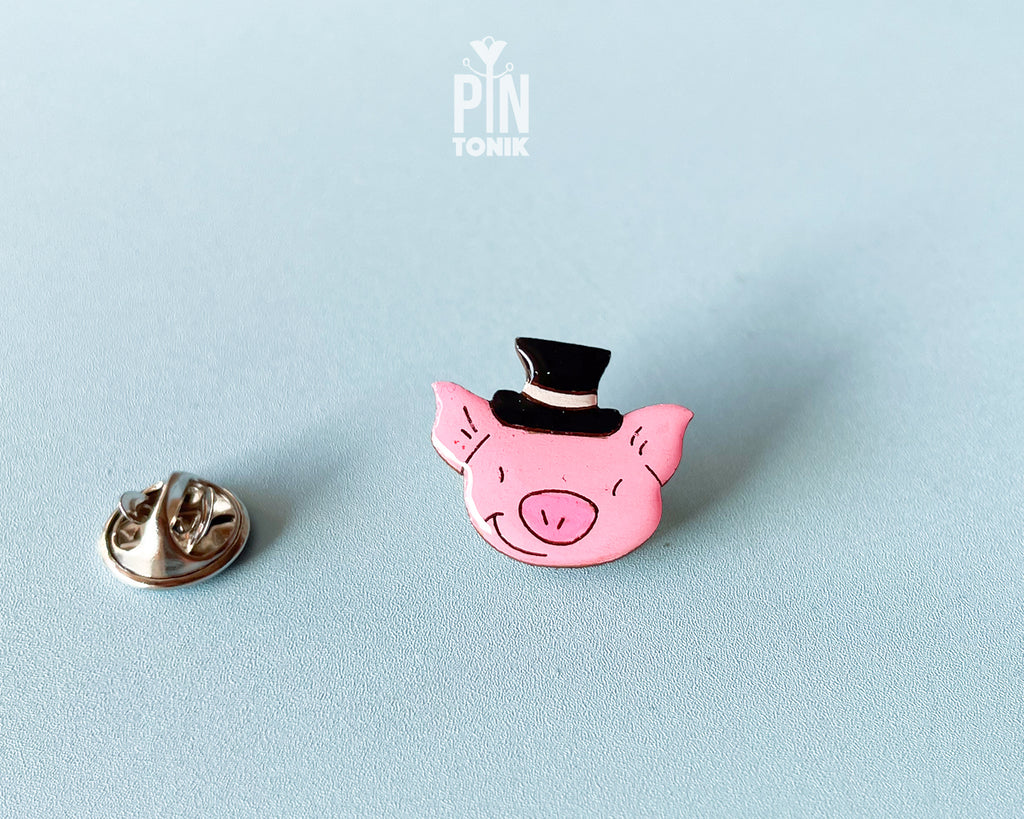 Hand-painted pink wooden pig pin wearing a black top hat with a high-gloss resin finish
