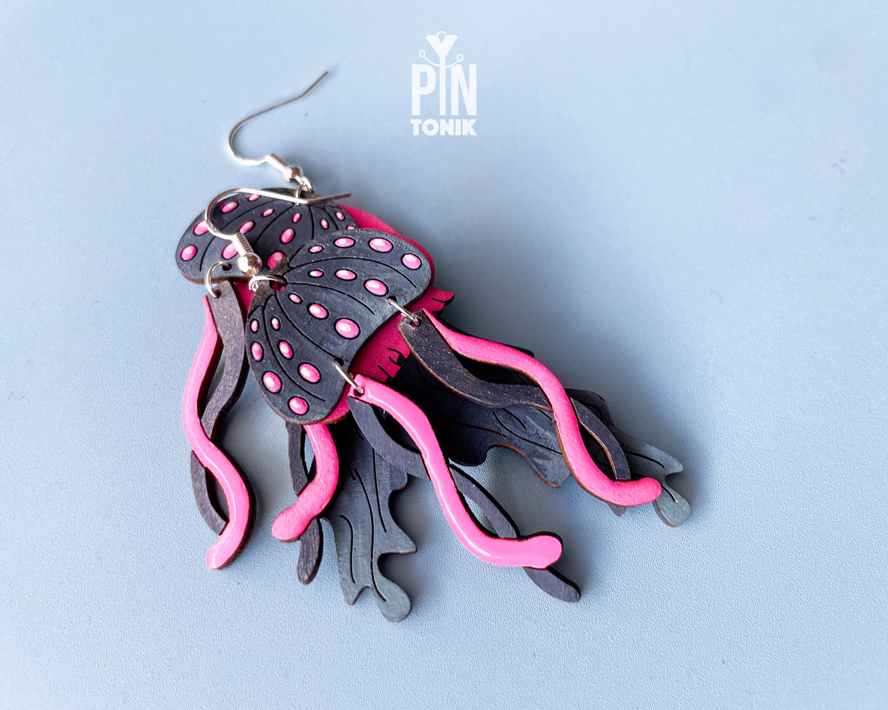 Hand-painted wooden jellyfish dangle earrings with charcoal grey bodies and vibrant neon pink tentacles on sterling silver hooks