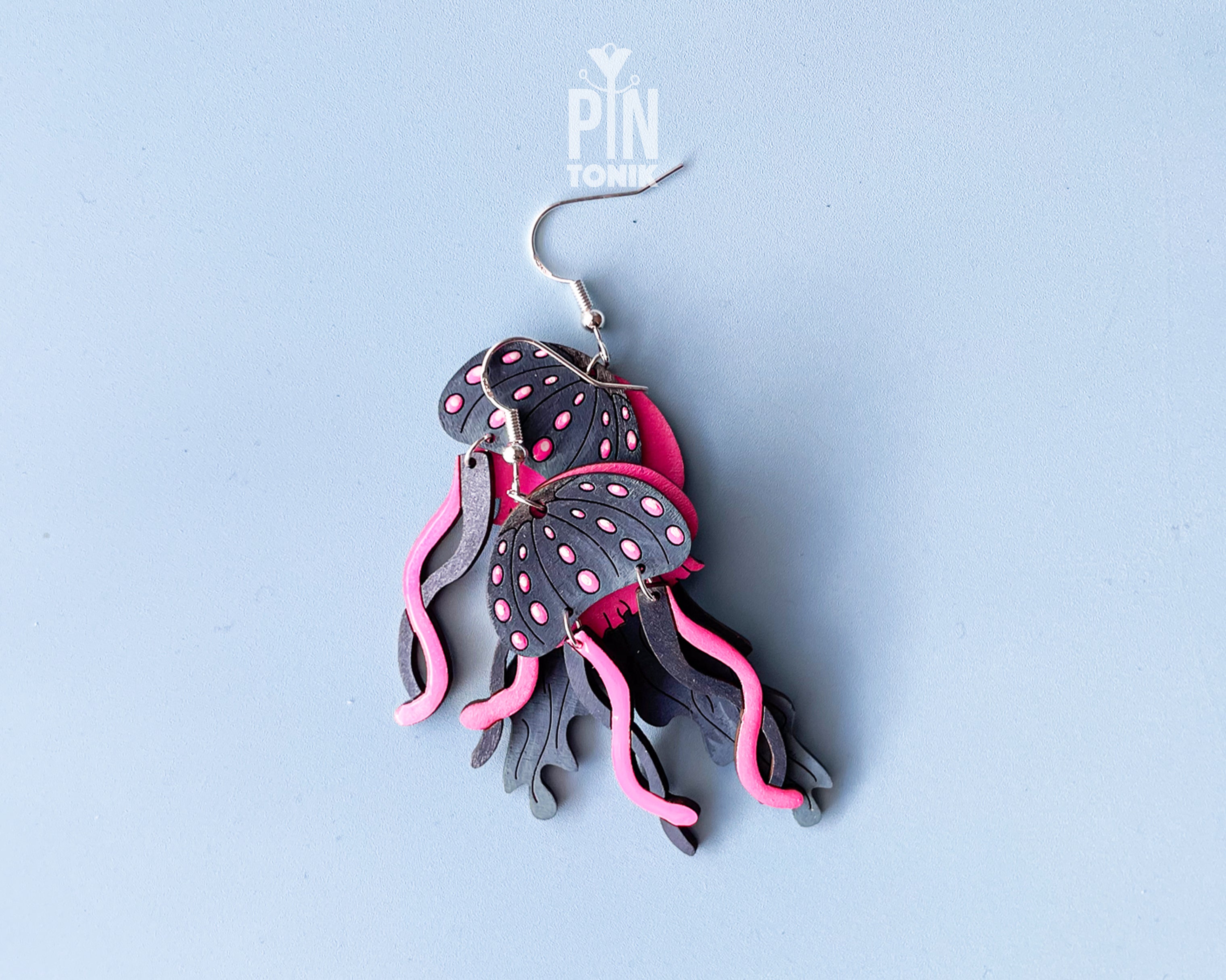 Hand-painted wooden jellyfish dangle earrings with charcoal grey bodies and vibrant neon pink tentacles on sterling silver hooks