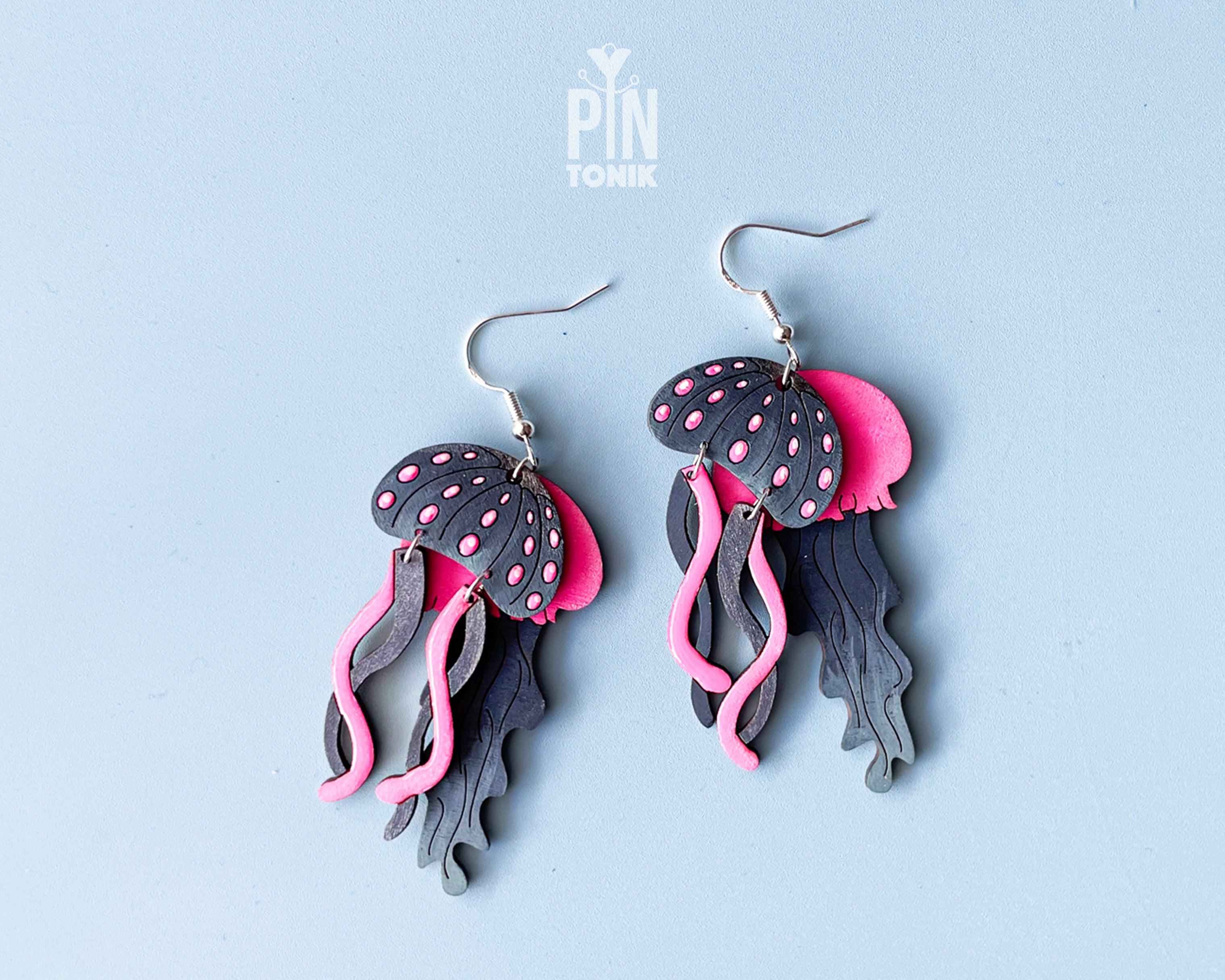 Hand-painted wooden jellyfish dangle earrings with charcoal grey bodies and vibrant neon pink tentacles on sterling silver hooks