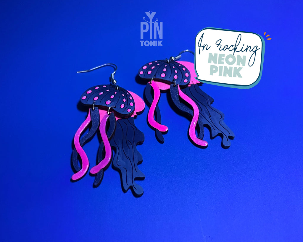 Hand-painted wooden jellyfish dangle earrings with charcoal grey bodies and vibrant neon pink tentacles on sterling silver hooks