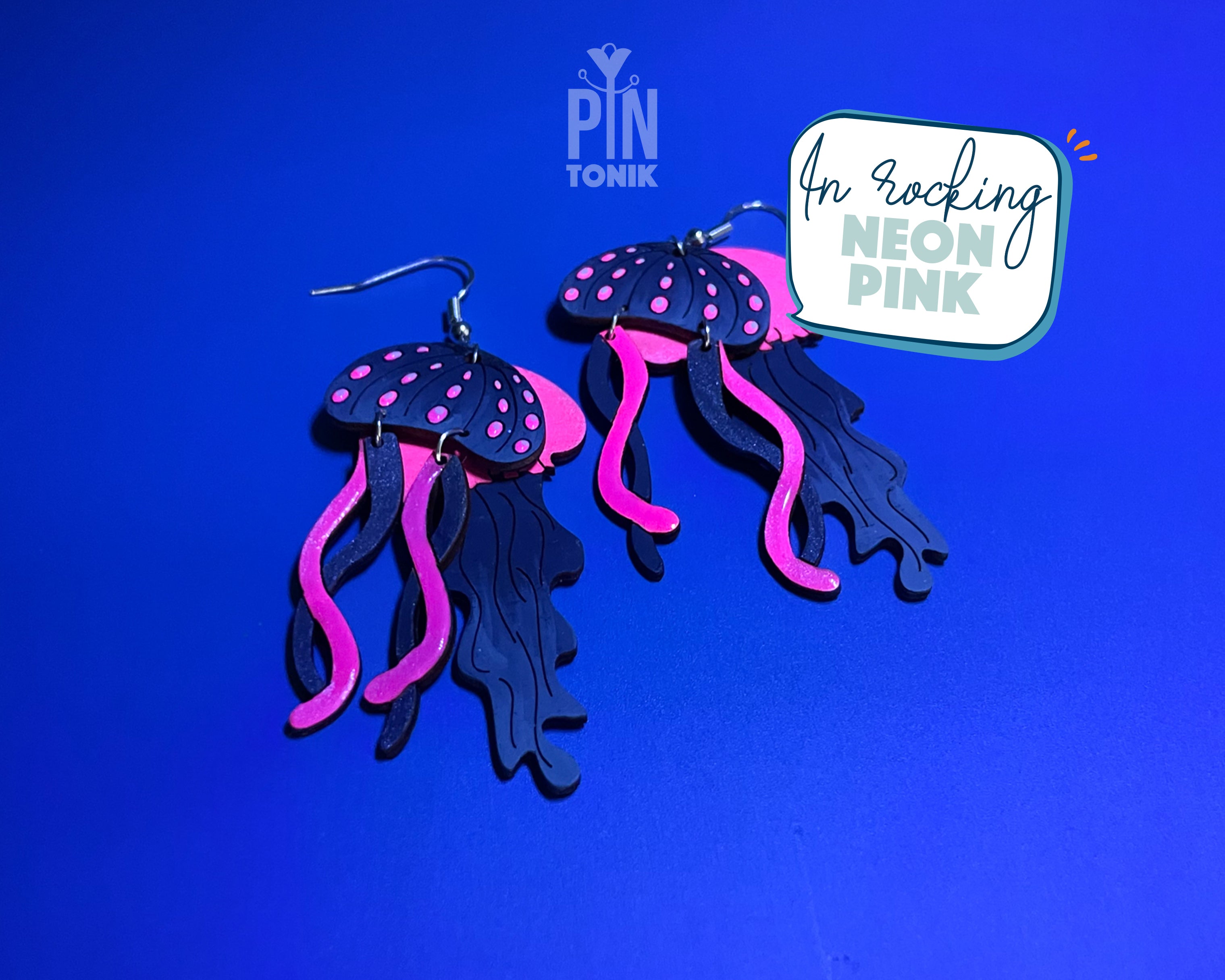 Hand-painted wooden jellyfish dangle earrings with charcoal grey bodies and vibrant neon pink tentacles on sterling silver hooks
