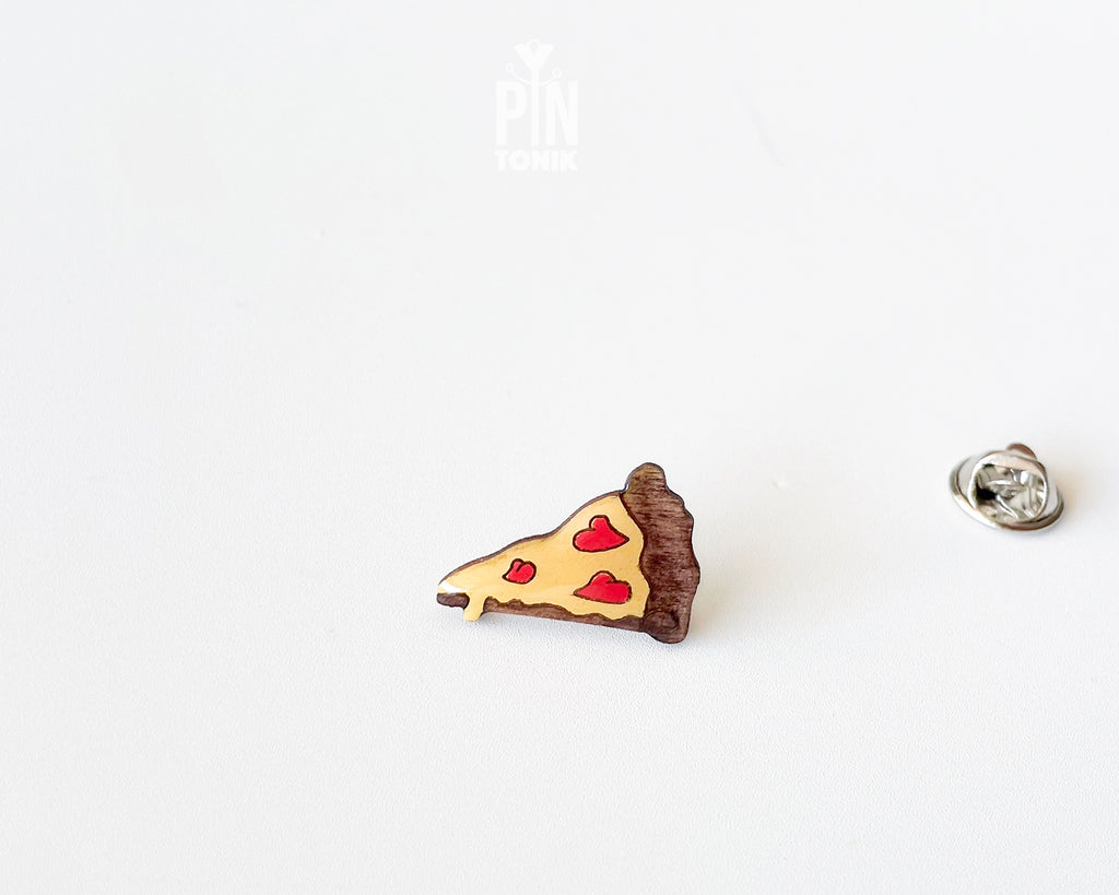 Hand-painted wooden pizza slice pin with heart-shaped pepperonis and a glossy finish, shown next to a stainless steel clutch back on a white background.
