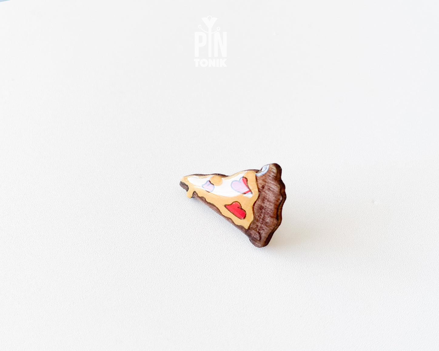 Hand-painted wooden pizza slice pin with heart-shaped pepperonis and a glossy finish, shown next to a stainless steel clutch back on a white background.