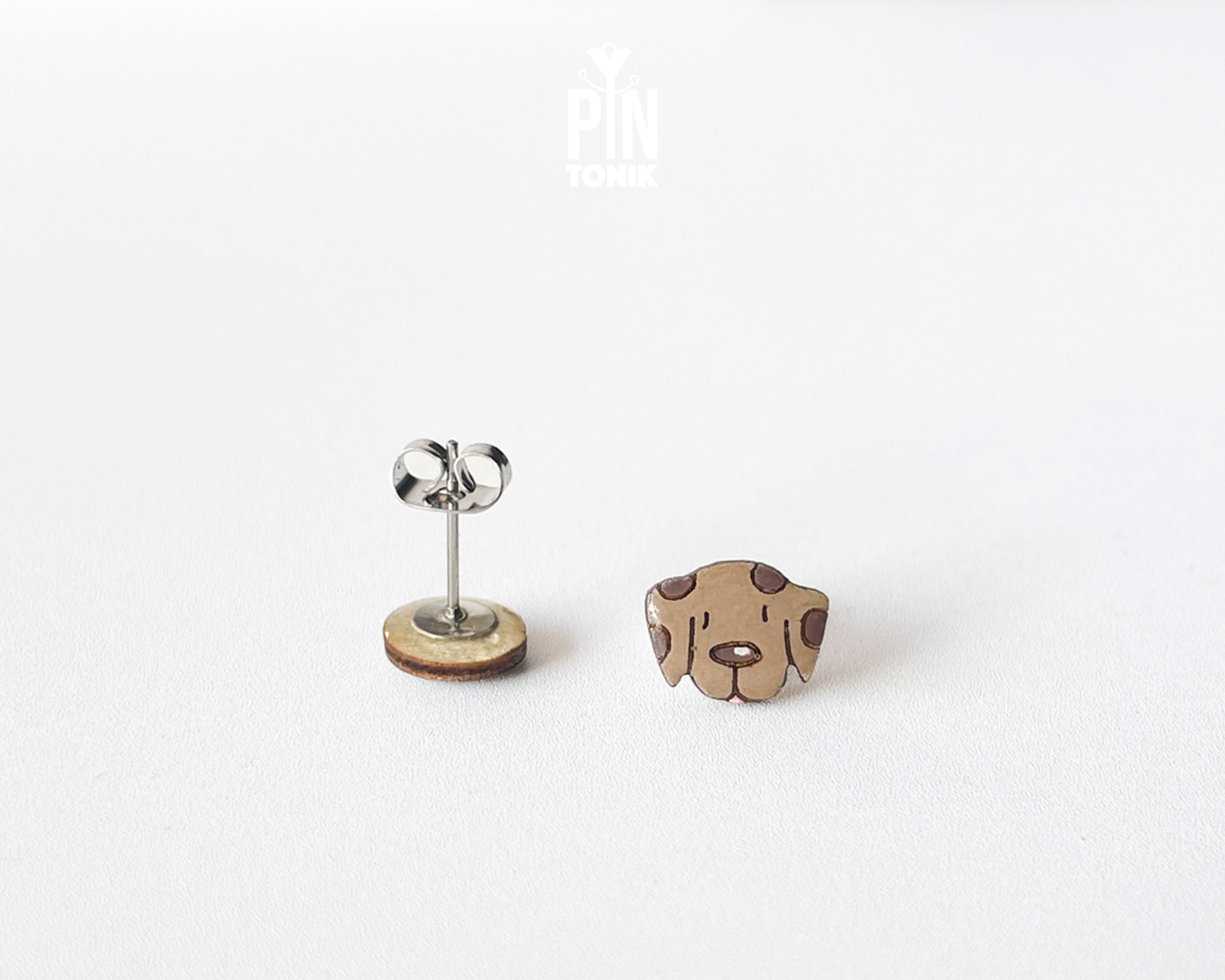 Mismatched hand-painted wooden stud earrings featuring a brown dog face and a matching paw print
