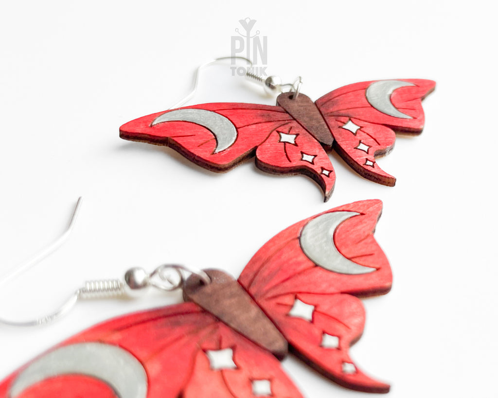 Hand-painted red wooden moth dangle earrings with silver crescent moon and white star details on sterling silver hooks