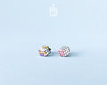 A pair of cube-shaped wooden stud earrings with colorful puzzle-cube faces, displayed on a light blue background with a 'PIN TONIK' logo at the top.