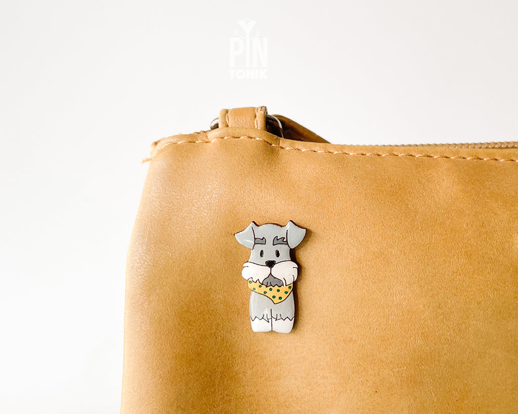 Hand-painted wooden schnauzer dog pin wearing a yellow polka-dot bandana with a glossy resin finish