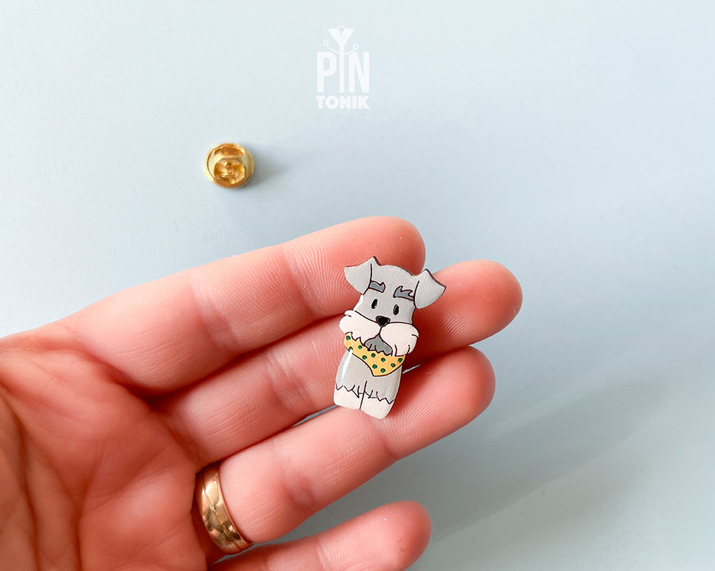 Hand-painted wooden schnauzer dog pin wearing a yellow polka-dot bandana with a glossy resin finish