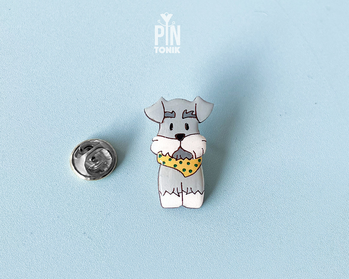 Hand-painted wooden schnauzer dog pin wearing a yellow polka-dot bandana with a glossy resin finish