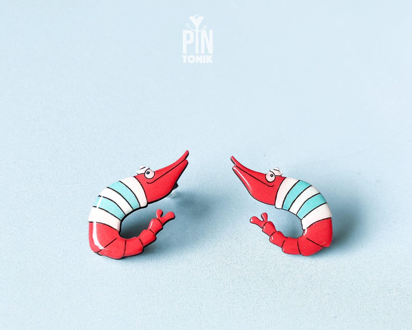 Pair of hand-painted wooden shrimp stud earrings with red and teal stripes and funny wide eyes