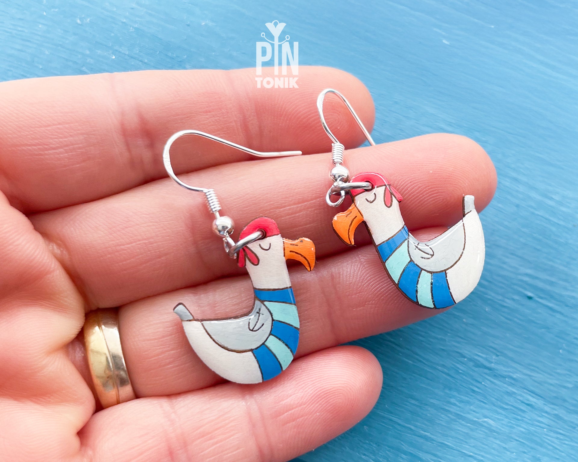 Hand-painted wooden seagull dangle earrings wearing a blue and white striped sailor sweater and a tiny hat on sterling silver hooks