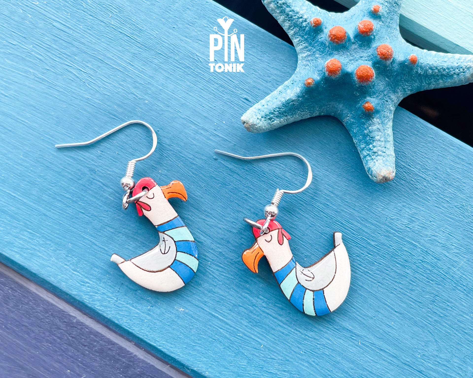 Hand-painted wooden seagull dangle earrings wearing a blue and white striped sailor sweater and a tiny hat on sterling silver hooks