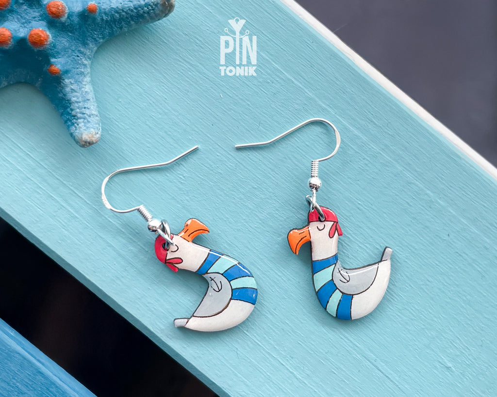 Hand-painted wooden seagull dangle earrings wearing a blue and white striped sailor sweater and a tiny hat on sterling silver hooks
